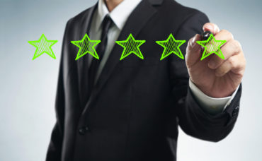Review, increase rating, performance and classification concept. Businessman draw five green stars to increase rating of his company, blank background.