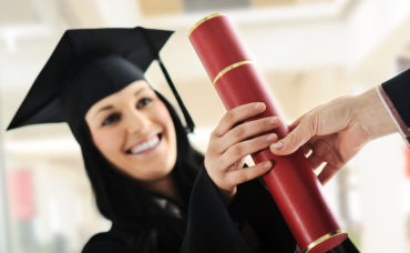 Young female graduating and receiving diploma at university